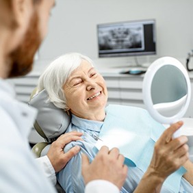a patient checking her new dental implants with a mirror