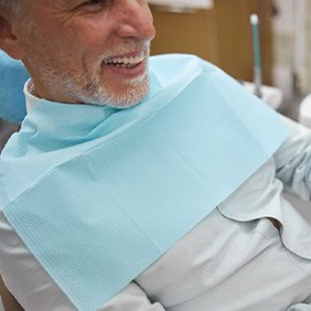 Older gentleman looking at his teeth in hand mirror