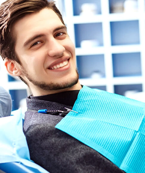 man leaning back in dental chair and smiling