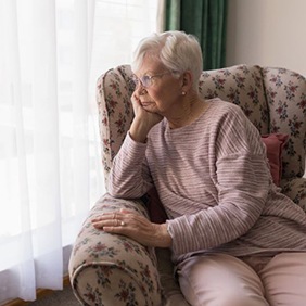 Sad older woman looking out her window