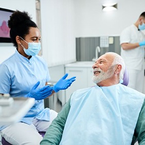 Happy senior man talking with dental team member