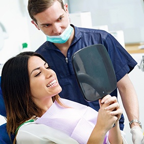 Dental patient holding mirror, looking at her teeth