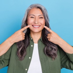 Happy, mature woman pointing at her smile