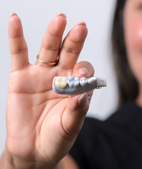 Dental team member holding up custom dental crowns