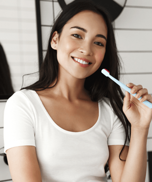 Woman standing in bathroom, holding toothbrush