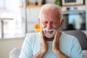 Frowning older man, dealing with discomfort of ill-fitting dentures